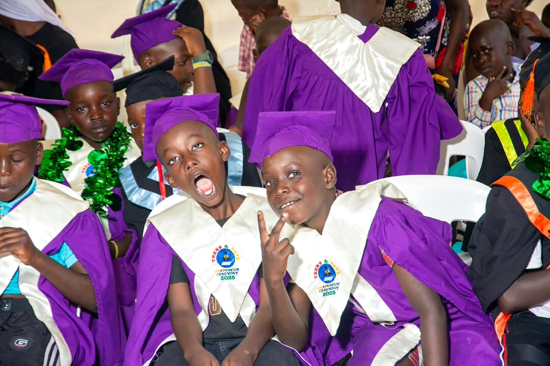 Children in graduation gowns celebrate at a school ceremony.
