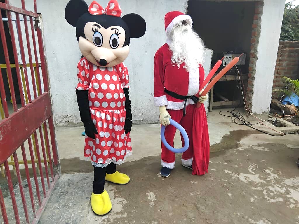 Character mascots pose by a school gate during a festive visit.